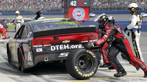 Jeff Gordon's team members complete a tire change in the pits late in the NASCAR Sprint Series auto race in Fontana, Calif., Sunday, March 23, 2014. Gordon was leading at the time, but a caution flag was displayed on the next to last lap, Kyle Busch (18) won the race in the 206th lap. (AP Photo/Alex Gallardo)