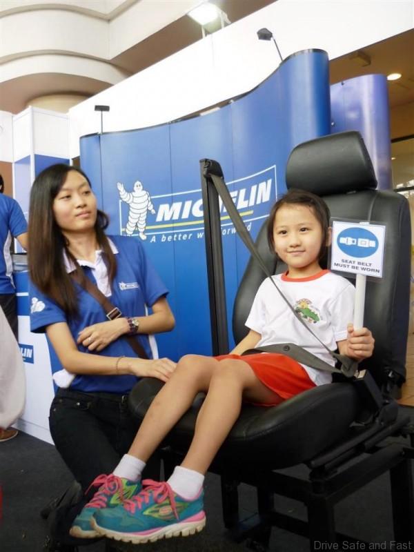 Michelin staff teaching the children on how to wear a seat belt correctly
